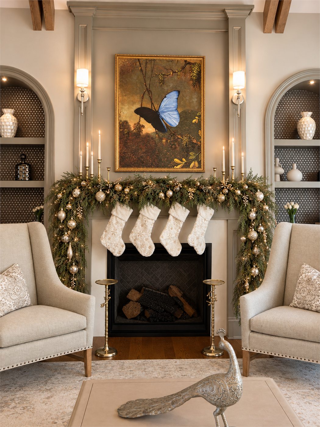 A fireplace mantel dressed with garland, silver and gold ornaments, and white stockings between arched built-ins